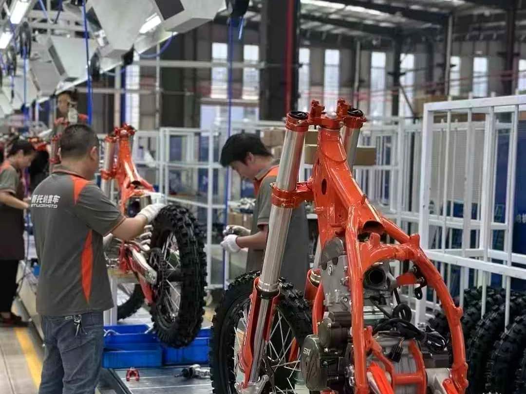 FCDC Motor worker checking an orange motorcycle frame on the assembly line