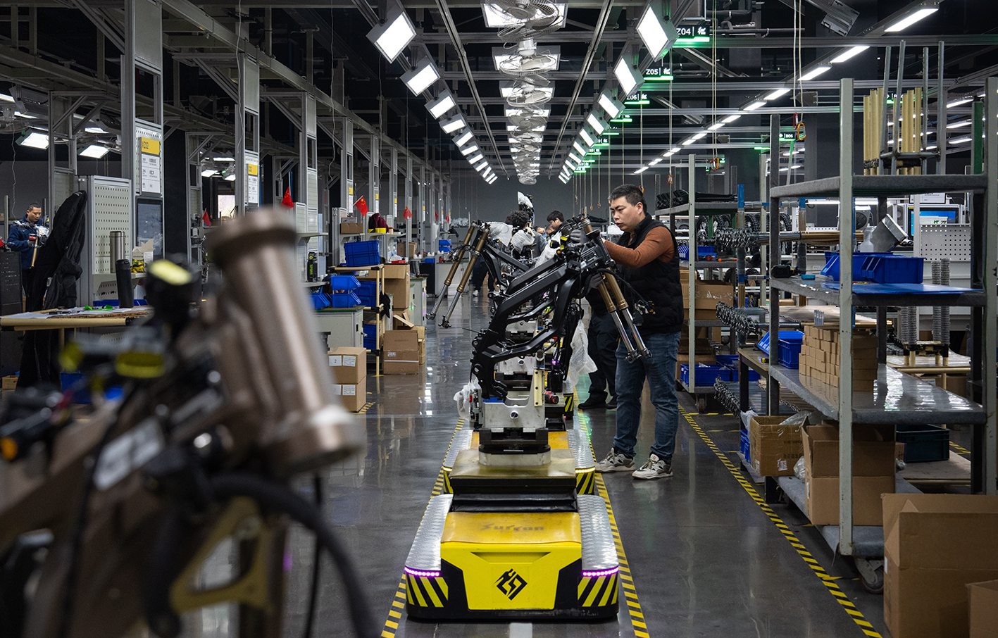 FCDC Motor worker inspecting a motorcycle frame at a factory assembly station