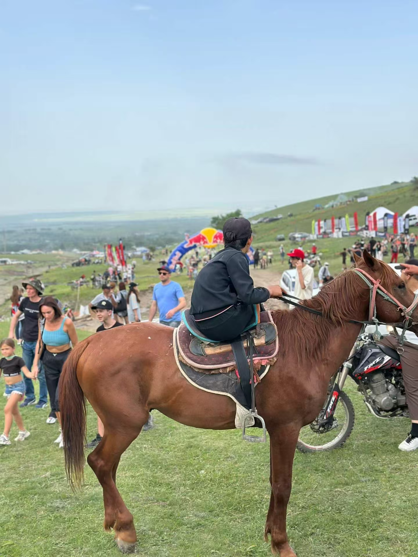 Crowd and riders at Kazakhstan motorcycle festival hillside