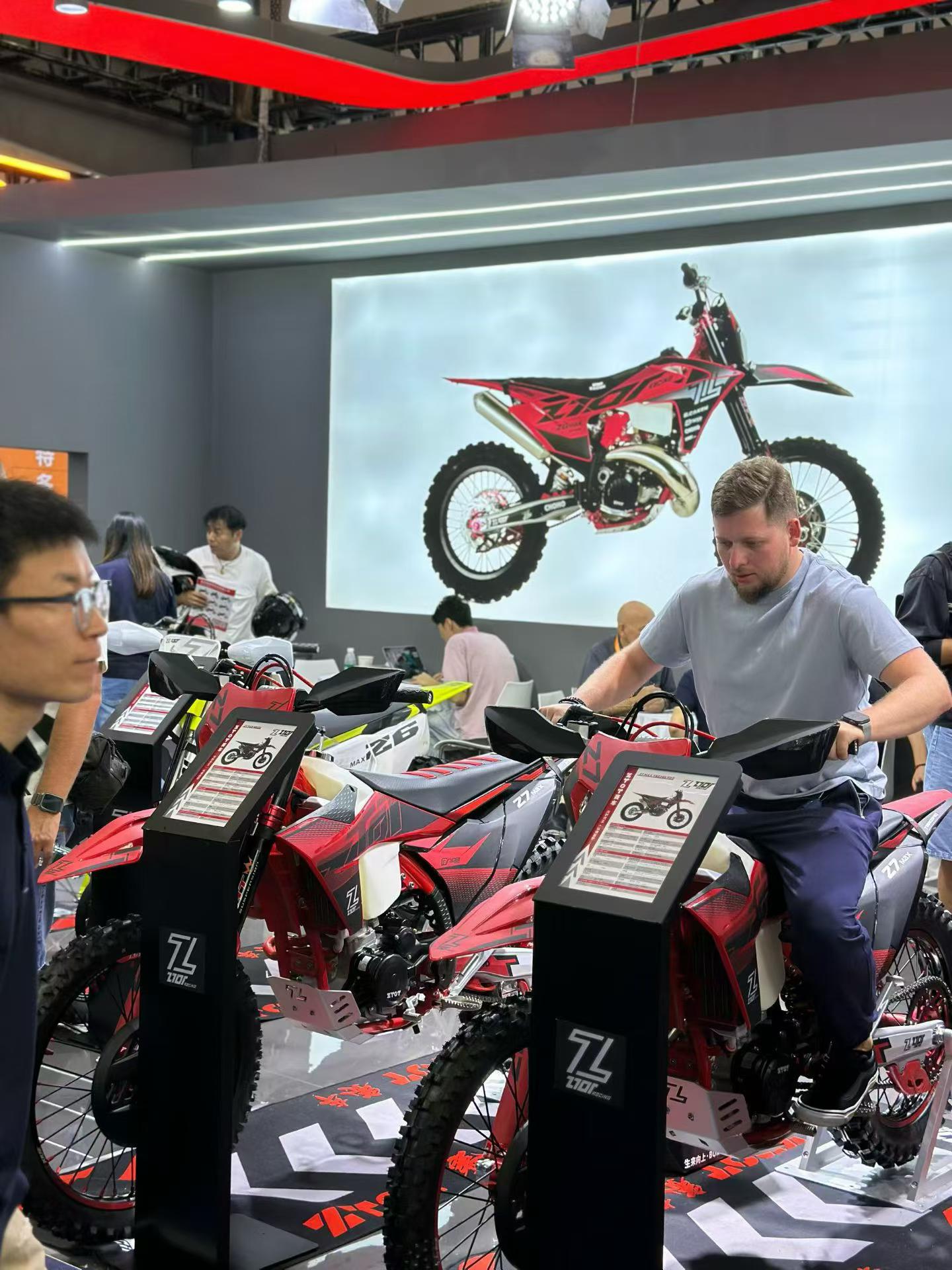 Besucher beim Probesitzen auf einem stehenden ZTOT-Motorrad mit den Händen am Lenker